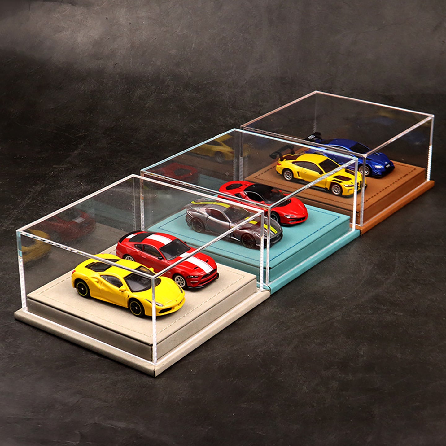 Collection of model cars displayed in a transparent acrylic case on a dark surface.
